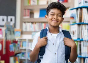 Young student with backpack in classroom smiling