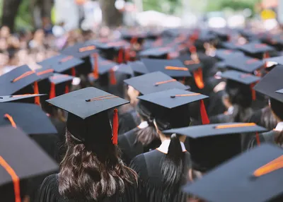 Group of high-school students in graduation caps walking to their graduation ceremony