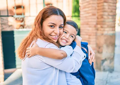 Mom hugging kid in front of school